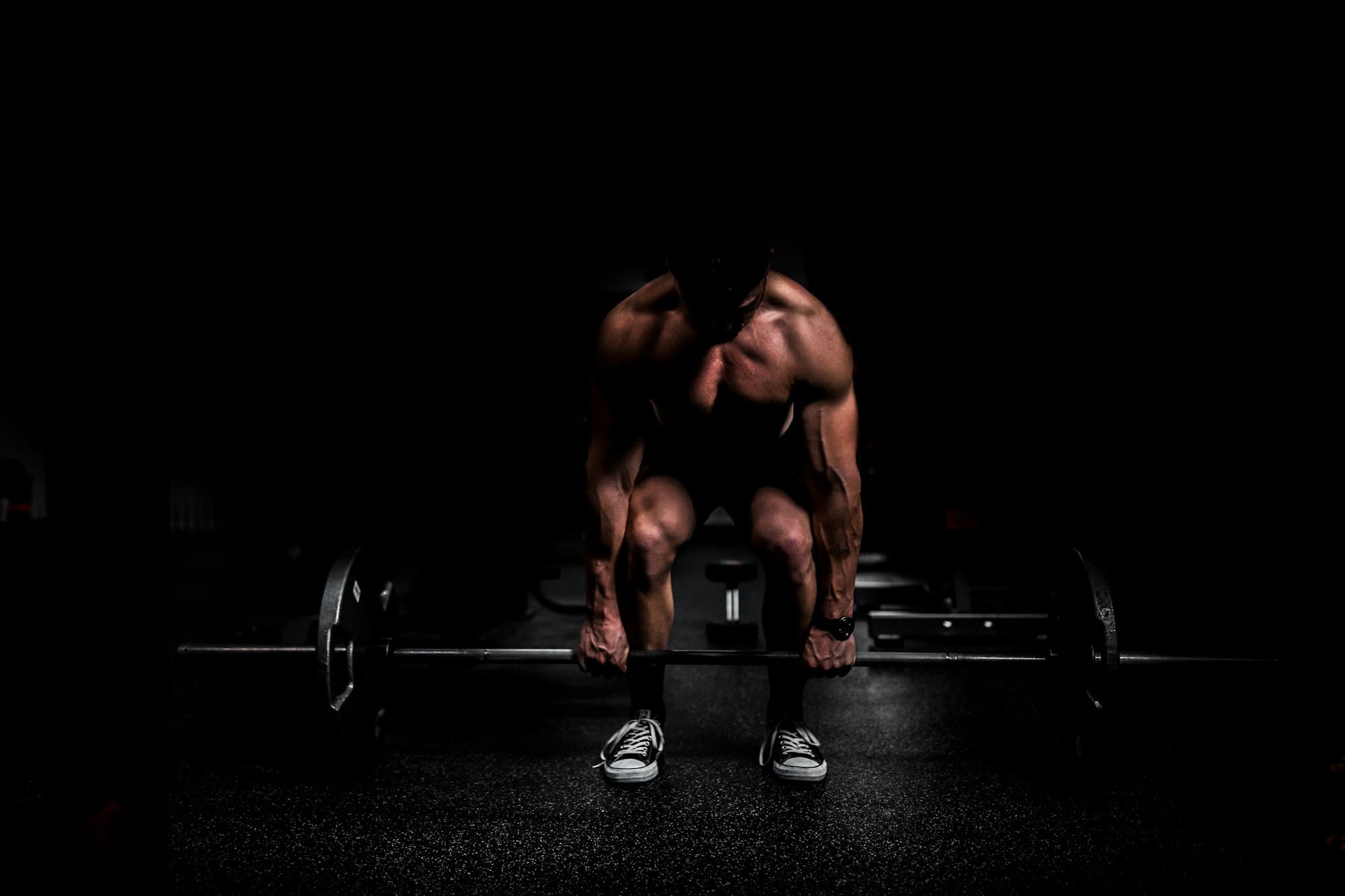 An athlete resting between heavy sets in a dark gym
