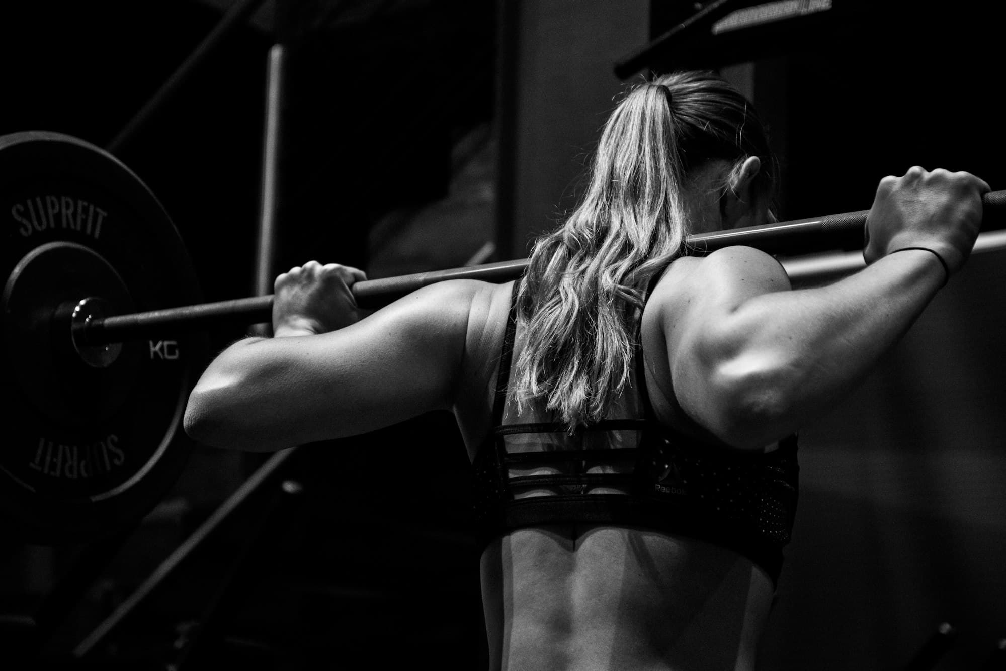 An athlete bracing under a loaded barbell back squat at Optimum Gym