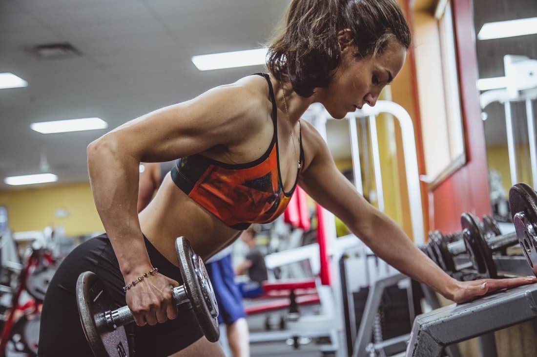 A coach guiding a member through a dumbbell set